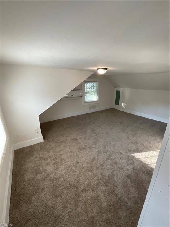 bonus room featuring vaulted ceiling and dark carpet