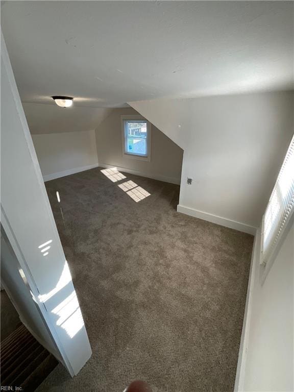 additional living space with vaulted ceiling and dark colored carpet