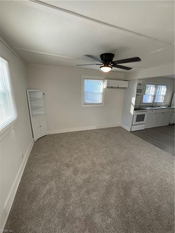 unfurnished living room with sink, dark carpet, a wall mounted air conditioner, and ceiling fan