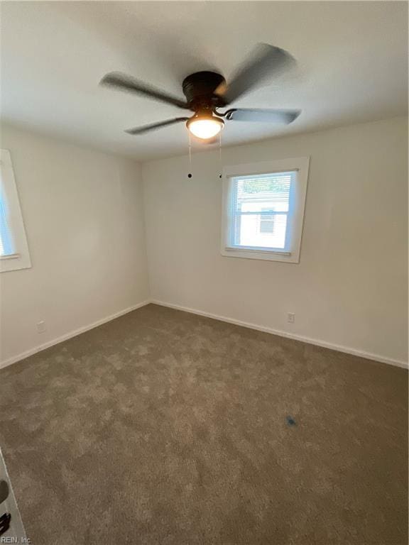 spare room featuring ceiling fan and dark colored carpet