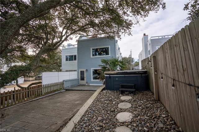 rear view of property with a patio area and a hot tub