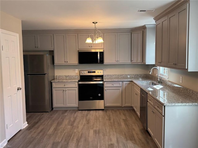 kitchen featuring sink, stainless steel appliances, light stone counters, dark hardwood / wood-style flooring, and decorative light fixtures