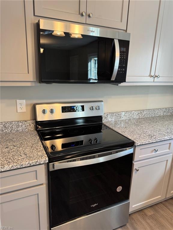 kitchen featuring light stone counters, stainless steel appliances, and light hardwood / wood-style flooring