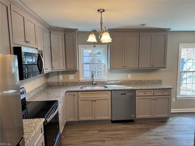 kitchen featuring pendant lighting, appliances with stainless steel finishes, light stone countertops, and sink