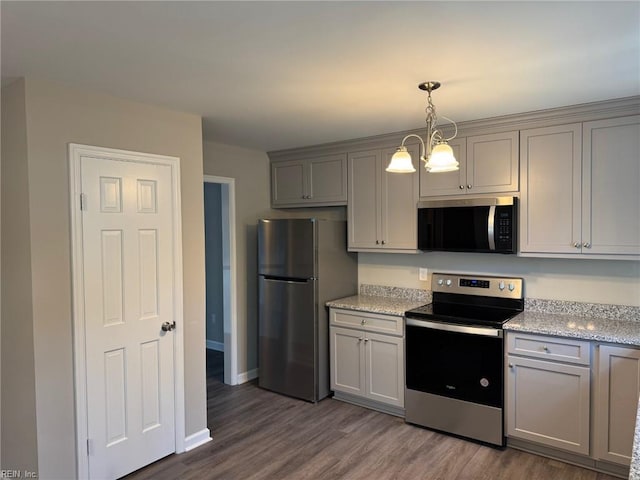 kitchen with decorative light fixtures, appliances with stainless steel finishes, dark hardwood / wood-style floors, gray cabinets, and light stone countertops