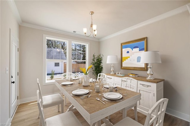 dining room with ornamental molding, light hardwood / wood-style floors, and a chandelier