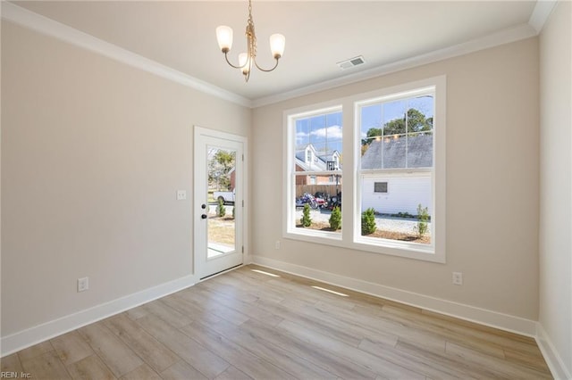 empty room with crown molding, a chandelier, and light hardwood / wood-style floors