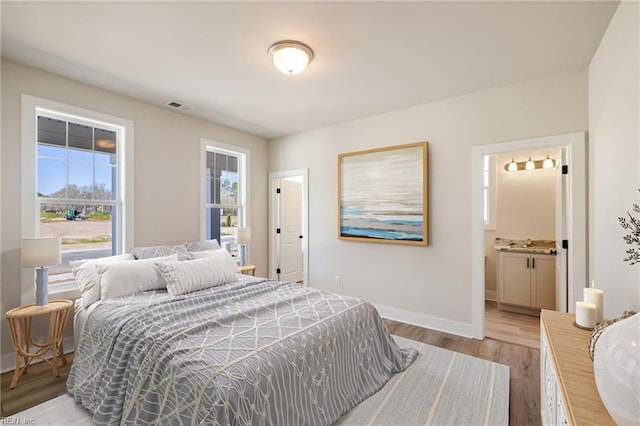 bedroom with connected bathroom and light hardwood / wood-style floors