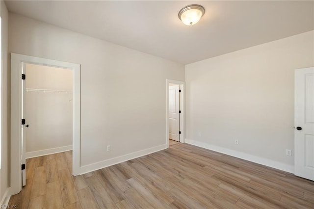 unfurnished bedroom featuring a closet, a spacious closet, and light hardwood / wood-style flooring