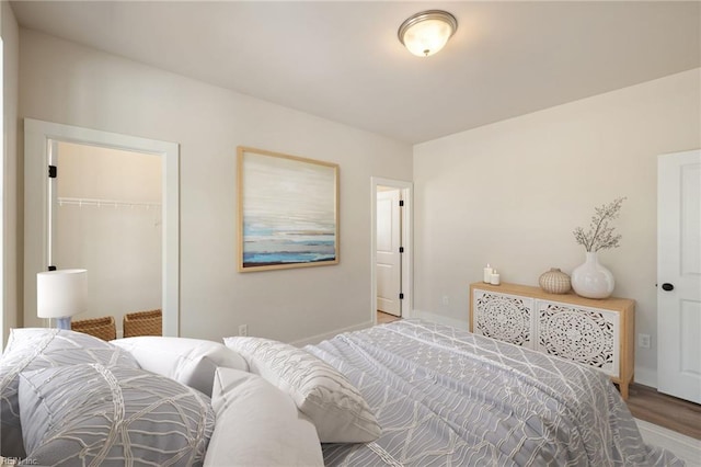 bedroom featuring a walk in closet, hardwood / wood-style floors, and a closet