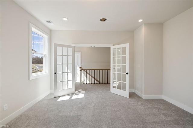 carpeted spare room featuring french doors