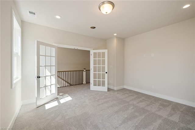 empty room featuring french doors and light colored carpet