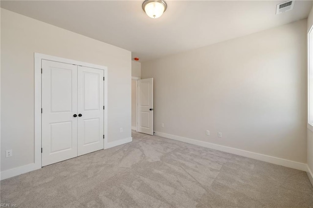 unfurnished bedroom with a closet and light carpet