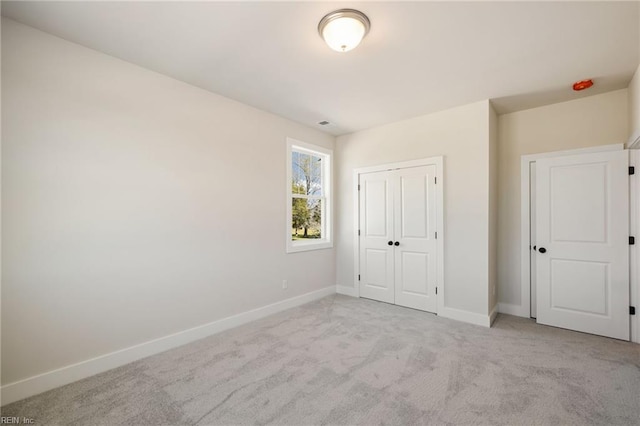 unfurnished bedroom featuring light colored carpet and a closet