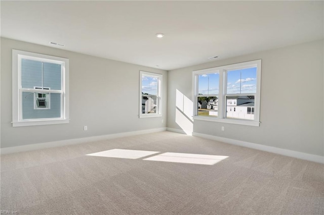 unfurnished room featuring plenty of natural light and light carpet