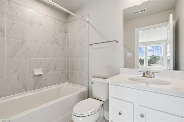 full bathroom featuring vanity, tiled shower / bath combo, and toilet