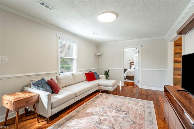 living room with dark hardwood / wood-style flooring, ornamental molding, and a textured ceiling