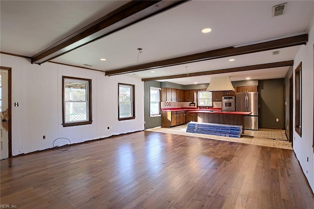 unfurnished living room with beamed ceiling and hardwood / wood-style floors