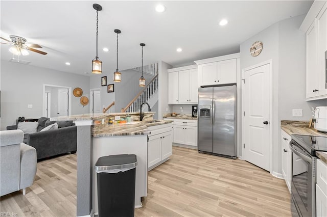 kitchen with sink, an island with sink, white cabinets, and appliances with stainless steel finishes