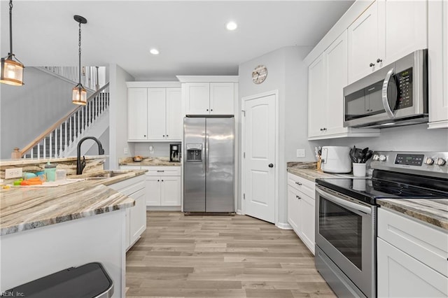 kitchen featuring stainless steel appliances, sink, pendant lighting, and white cabinets