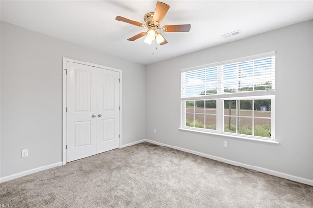 unfurnished bedroom with ceiling fan, a closet, and light carpet