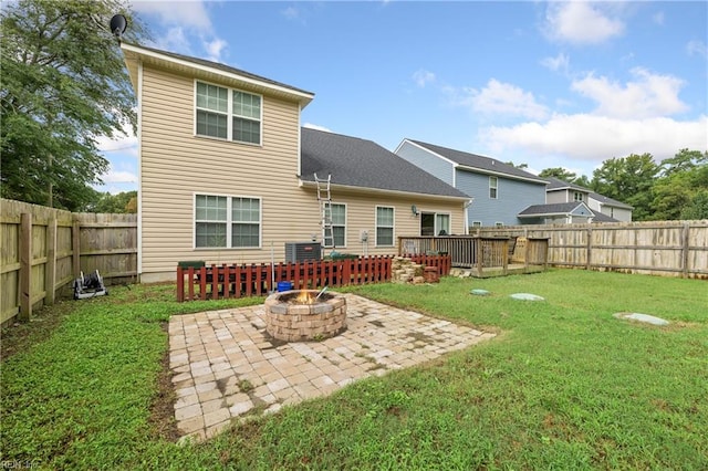 back of property with a wooden deck, a fire pit, a patio area, and a lawn