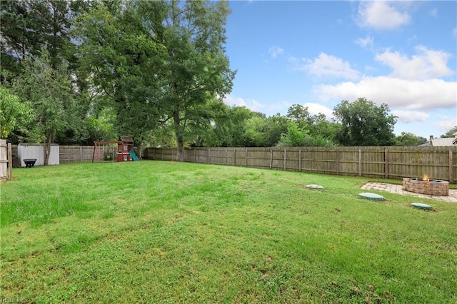 view of yard featuring a playground and an outdoor fire pit