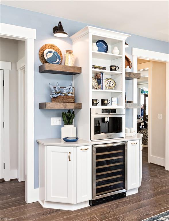 bar featuring white cabinets, oven, dark wood-type flooring, and beverage cooler