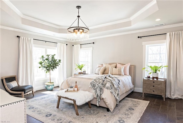 bedroom with dark hardwood / wood-style flooring, a tray ceiling, ornamental molding, and a chandelier