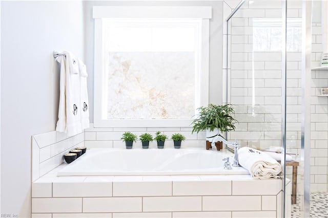 bathroom featuring plenty of natural light and a relaxing tiled tub