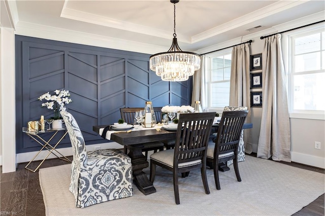 dining space featuring an inviting chandelier, ornamental molding, and a tray ceiling