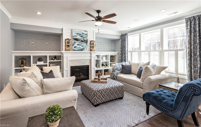 living room with hardwood / wood-style flooring, crown molding, a stone fireplace, and ceiling fan