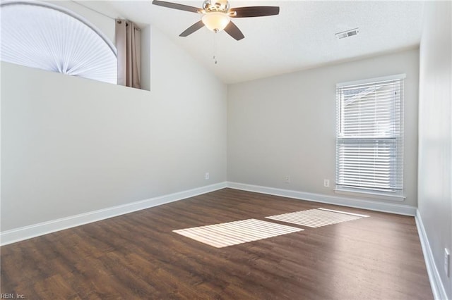 empty room with plenty of natural light, dark hardwood / wood-style floors, lofted ceiling, and ceiling fan