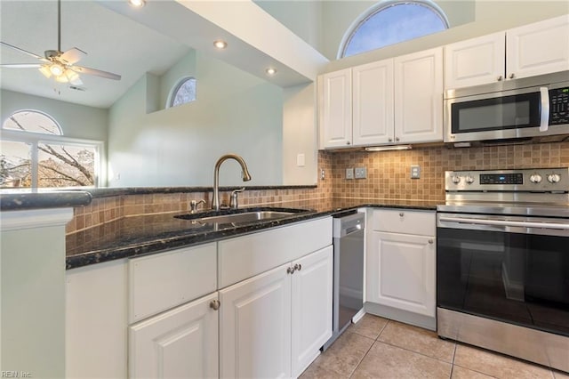 kitchen featuring white cabinetry, sink, dark stone counters, and appliances with stainless steel finishes