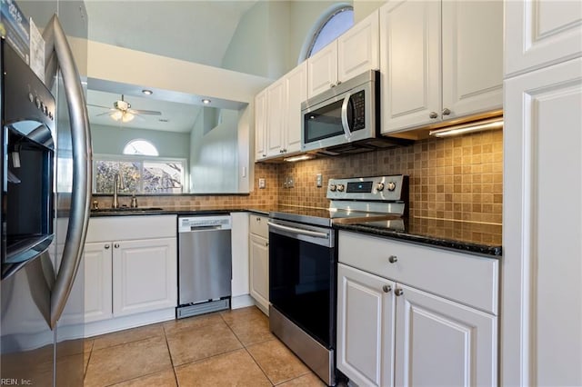 kitchen with vaulted ceiling, appliances with stainless steel finishes, sink, and white cabinets