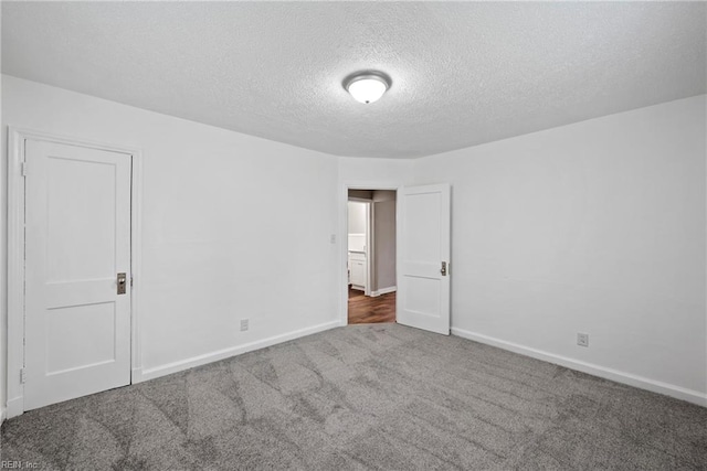 empty room featuring dark carpet and a textured ceiling