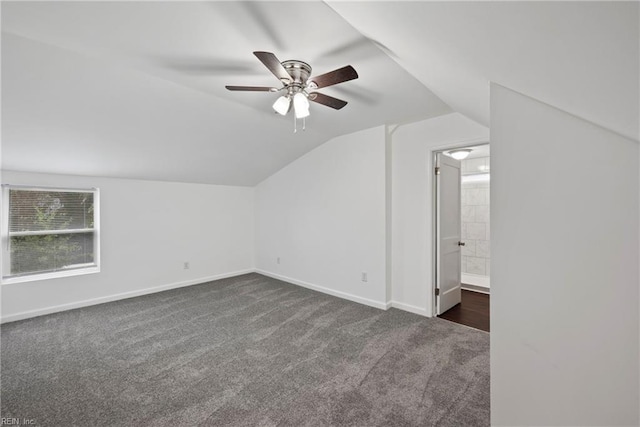 additional living space with dark carpet, ceiling fan, and vaulted ceiling