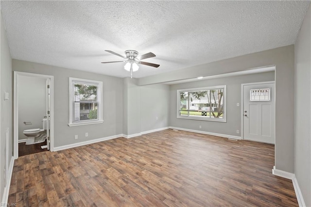 interior space with ceiling fan, a healthy amount of sunlight, dark hardwood / wood-style flooring, and a textured ceiling