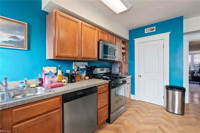 kitchen with sink, light parquet flooring, and appliances with stainless steel finishes