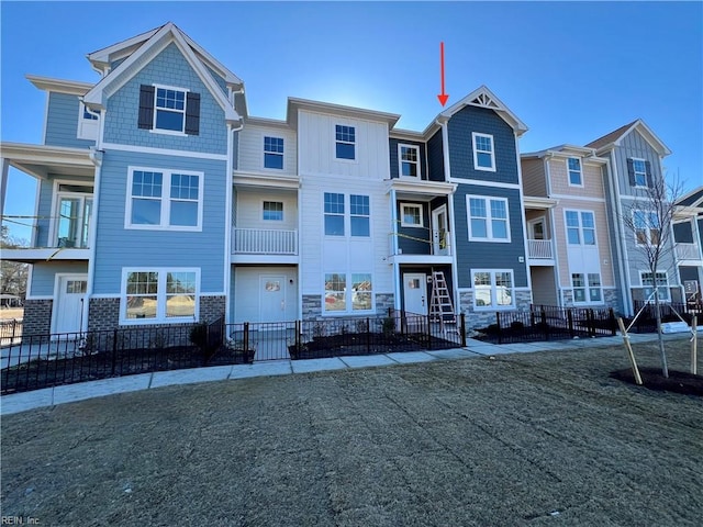 multi unit property featuring a fenced front yard and stone siding