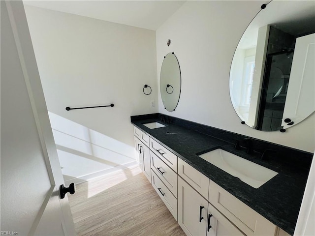 bathroom with hardwood / wood-style flooring, vanity, and a shower