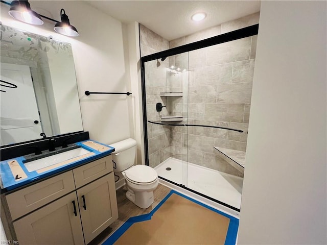 bathroom with wood-type flooring, toilet, vanity, and walk in shower