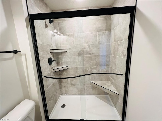 bathroom with toilet and a shower with shower door