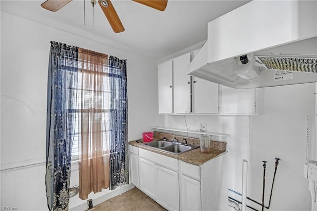 kitchen with sink, white cabinetry, island range hood, light tile patterned floors, and ceiling fan