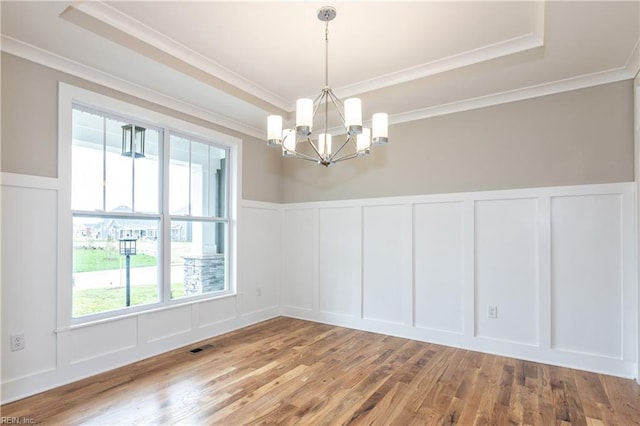 spare room featuring wood-type flooring, ornamental molding, and a raised ceiling