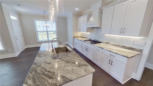 kitchen with light stone counters, sink, a center island with sink, and white cabinets