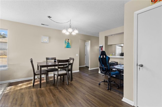 dining space with dark hardwood / wood-style floors, a wealth of natural light, and an inviting chandelier