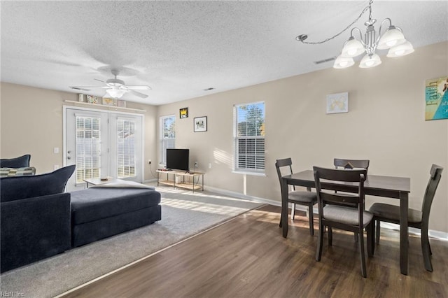 living room with dark wood-type flooring, ceiling fan with notable chandelier, and a textured ceiling