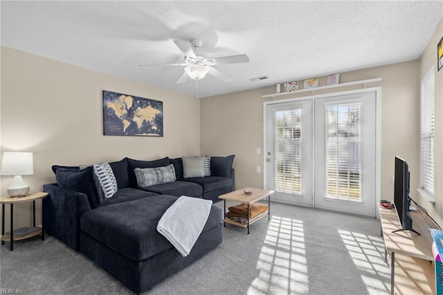 living room featuring ceiling fan, light colored carpet, a textured ceiling, and french doors