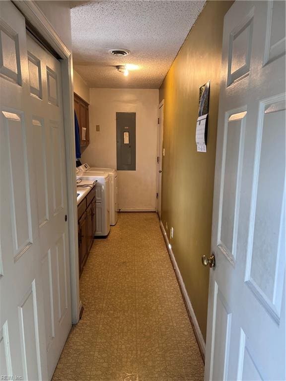 laundry area featuring washing machine and dryer, electric panel, cabinets, and a textured ceiling